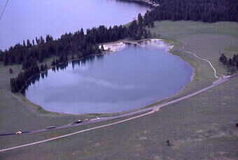 Aerial photo of the 0.06 square mile (0.16 square kilometer) Indian Pond hydrothermal explosion crater north of Yellowstone Lake. The deposits from the explosion that formed the crater were dated with radiocarbon to 2,900 years ago. Photo from Yellowsto...